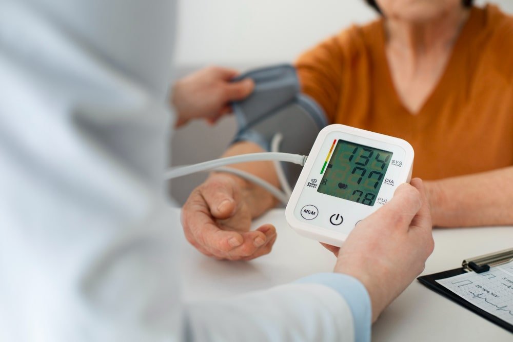 Rancho, California clinic close-up of a healthcare professional checking an elderly patient’s blood pressure with a digital monitor.
