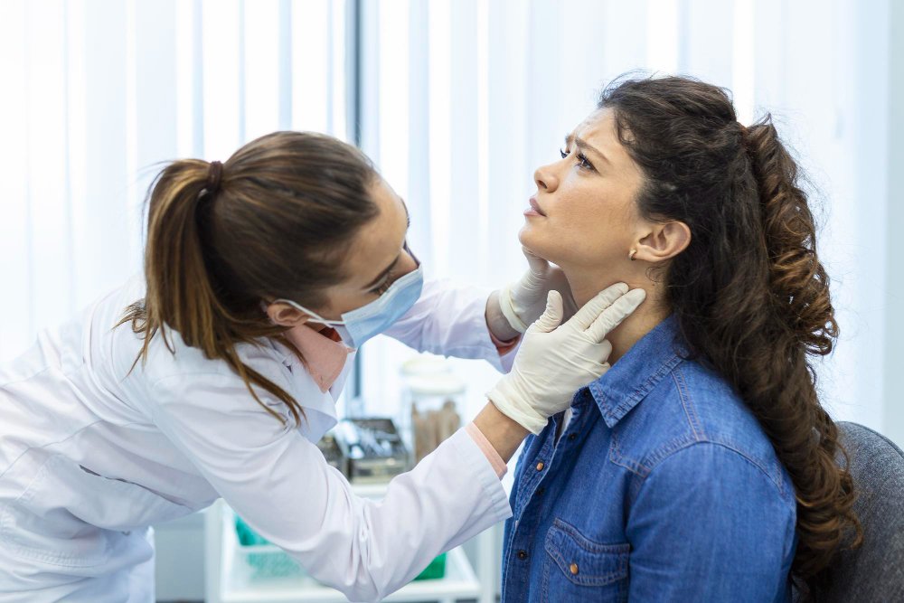 Rancho, California clinic with a female doctor examining a patient’s neck and throat for abnormalities.